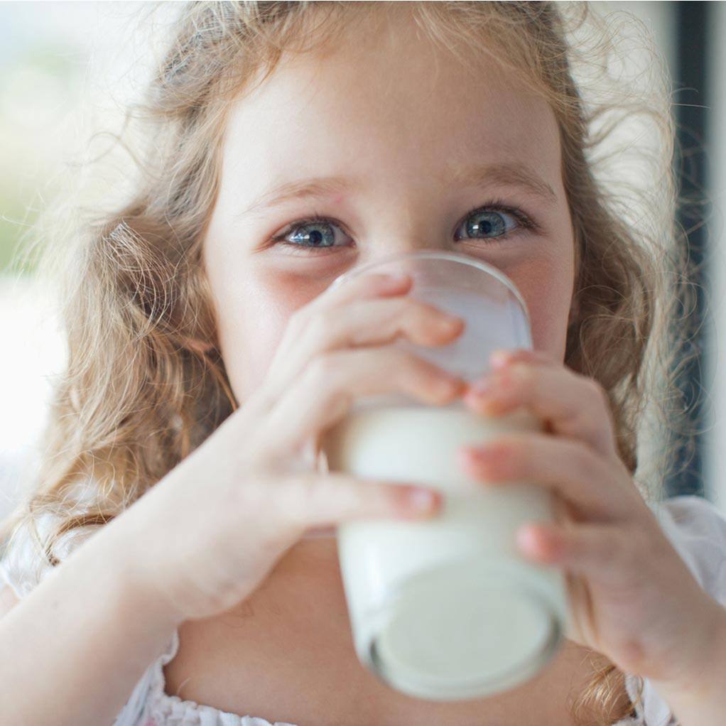 A young girl drinking a nice glass of milk